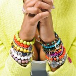 NTY Clothing Exchange model wearing about 20 bracelets in various colors on both wrists, hands folded together