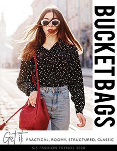 Young fashionable woman holding red bucket style handbag outdoors with sunglasses on